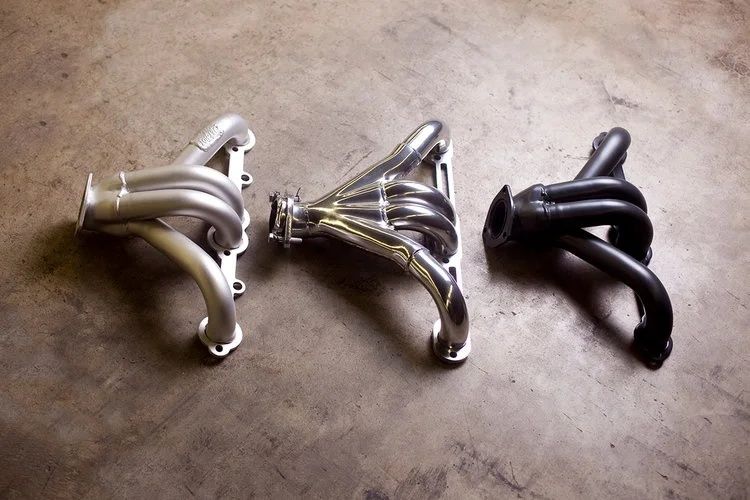 Three exhaust headers with polished, silver, and black finishes