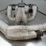 Heat-wrapped exhaust manifold and pipes displayed on a metal surface