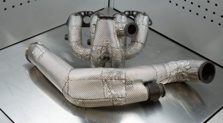 Heat-wrapped exhaust manifold and pipes displayed on a metal surface